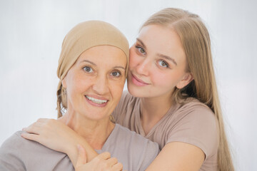A young and beautiful daughter cuddles her mother's cancer patient and fortifies her to fight during the chemotherapy. Concept for love and support from beloved and family to breast cancer people