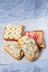 Delicious toasted sandwich bread with peanut butter, banana, honey, chia seeds on concrete background. Healthy, balanced traditional American school breakfast. Vegan sweet dessert. 