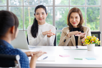 Fototapeta premium Deaf translator teaching two businesswomen to use and understand hand language sign