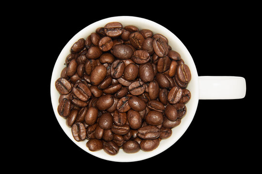 Coffee beans in ceramic cup isolated.  Image cut and placed on black background. Flat lay