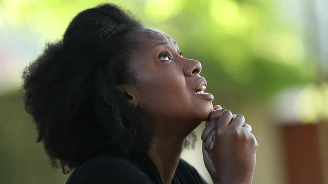 Worried black woman looking for hope and faith. African lady praying to God