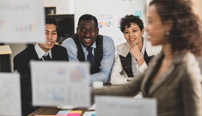 Selective focus on Attendee. Businesswomen smilling explaining the attendees smilling and on a board, having graph papers at the conference room in the office. Concept meeting teamwork.