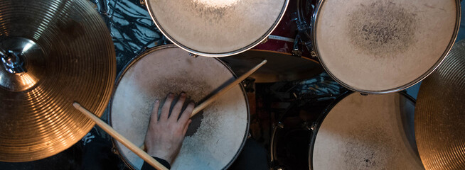 Professional drum set closeup panorama banner. Man drummer with drumsticks playing drums and...
