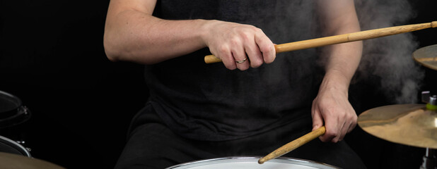 Professional drum set closeup panorama banner. Man drummer with drumsticks playing drums and cymbals, on the live music rock concert or in recording studio   