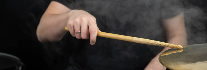 Fototapeta premium Professional drum set closeup panorama banner. Man drummer with drumsticks playing drums and cymbals, on the live music rock concert or in recording studio 