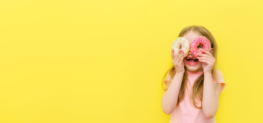 World Donut Day or No diet day. A little girl holding donuts and smiling, holding on a yellow...