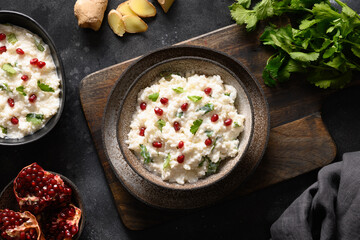 Homemade Curd Rice with pomegranate, cilantro, ginger on a black background. Top view. Traditional...