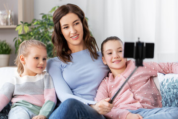 family, technology and people concept - happy mother and daughter with smartphone taking selfie at home