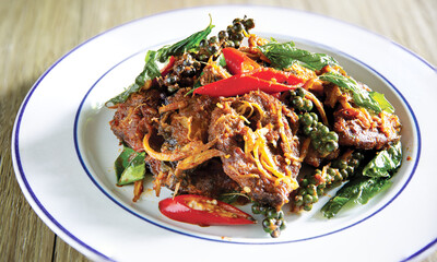 Crispy fried Catfish with curry paste in white dish on brown wooden table. Thai food
