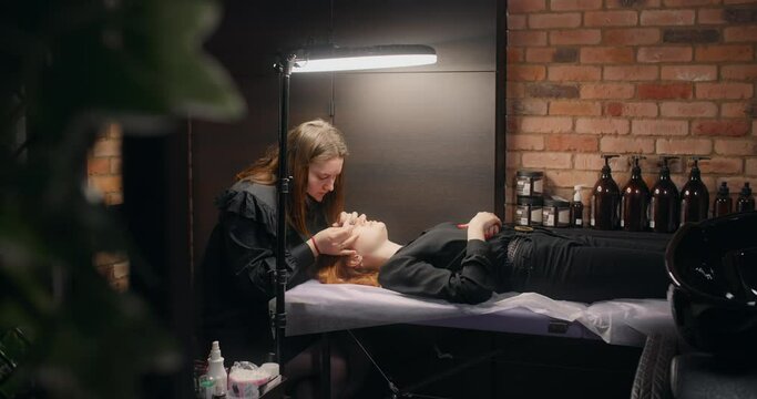 Lashmaker does the eyelash lamination procedure for the client in the beauty salon, cosmetic services, beauty care procedures, 4k 60p Prores HQ