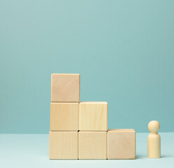 wooden figurine of a man stands on a staircase made of blocks on the first step