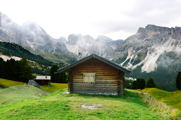 Old wooden shelters in Dolomites mountain. In the background Sassolungo peak.