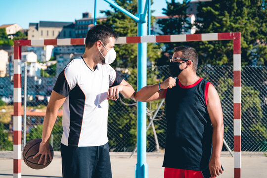 Two Friends With Masks Greet Each Other Before Starting To Play Basketball