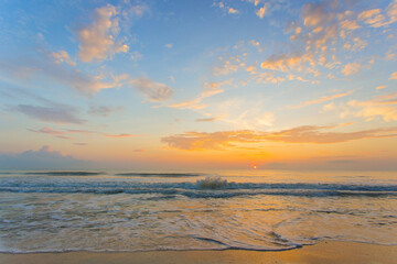 Fototapeta premium A picture of the sea is lapping the sand beach in evening sunset. Blue orange sky with sea view background.