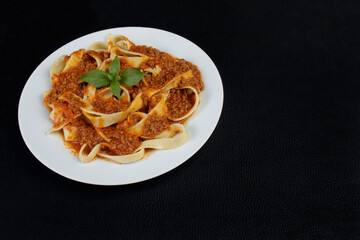 Pasta with bolognese sauce and basil leaves. Pasta popular all over the world of Italian origin. Gastronomy photo with space for texts.