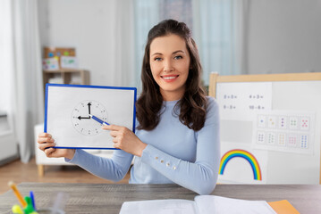 distant education, primary school and teaching concept - happy smiling female teacher with analog...