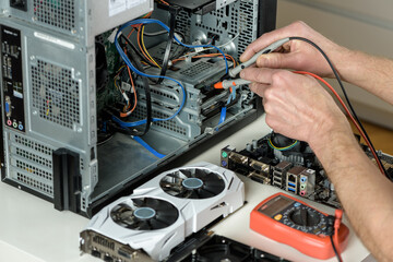 The repairman checks the serviceability of the computer with a multimeter.