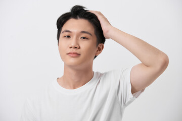 Young handsome man wearing white t-shirt over isolated background Smiling confident touching hair with hand up gesture
