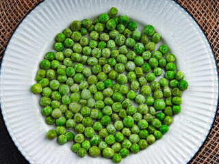 Tasty green peas in a white plate. Top view. 