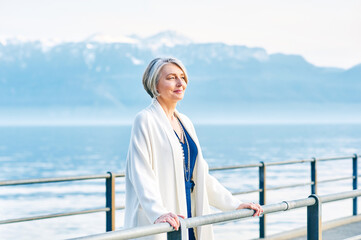 Beautiful middle age woman admiring amazing view of winter lake and mountains