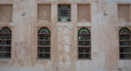 Fototapeta na wymiar Front view of an Arabic old wall with traditional wooden windows and door in Qatar.