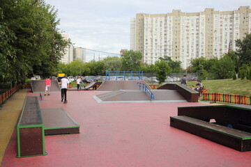 Modern outdoor urban skatepark with skateboarders on ramps in Moscow district Nagatino at Sunny...