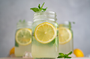 three Lemon mojito cocktail with mint in mason jars on top of wood. lemon mojito