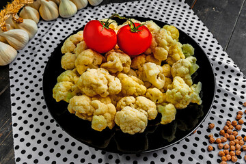 Cauliflower on a black plate. Vegetables on the kitchen table. 