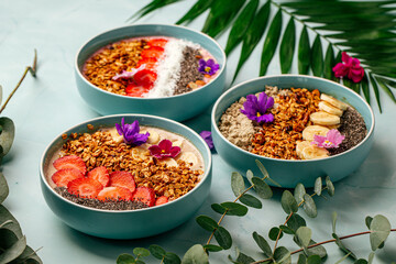 Side view on dfferent smoothie bowls with fruits and granola 