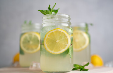 three Lemon mojito cocktail with mint in mason jars on top of wood. lemon mojito