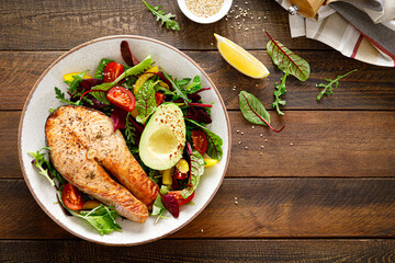 Salmon fish steak grilled, avocado and fresh vegetable salad with tomato, bell pepper and leafy vegetables