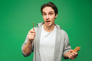 Young man holds straw, isolated on green background