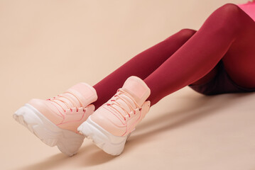 Modern sneakers on the women feet in red stockings close up.