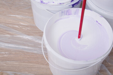 close-up of a paint bucket and a mixing mixer, against a white wall