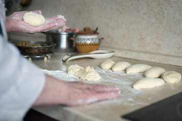 the hands of an elderly cook sculpt dough blanks for a pie