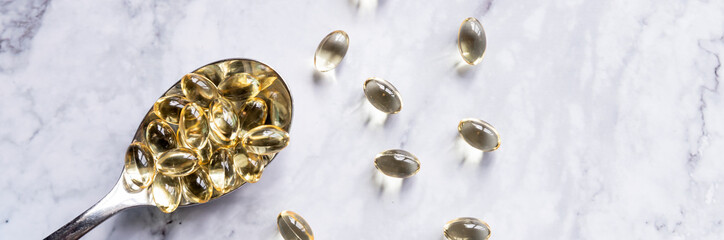 fish oil capsules on spoon isolated on marble background.Healthy Vitamins, supplements ,Omega 3. Healthy lifestyle.Copy space.web banner