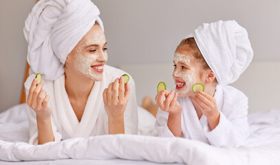 Mother and daughter resting on bed during skin care procedure