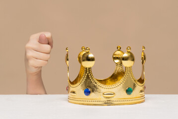 Women hand shows a fig gesture and a golden crown on the table. Unwillingness to give up power...