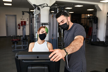 Personal trainer and sporty woman exercising wearing face masks during pandemic