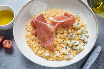 Pumpkin risotto served with prosciutto ham and gorgonzola cheese in a beige plate, selective focus, studio shot