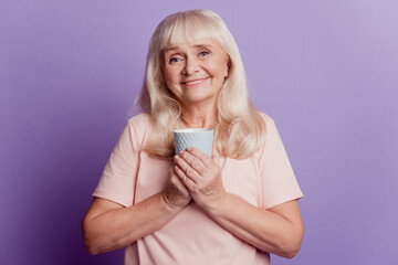 Photo of old woman hold tea coffee cup isolated on purple background