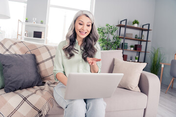 Photo portrait of elder woman sitting in room typing using laptop talking on meeting with web camera