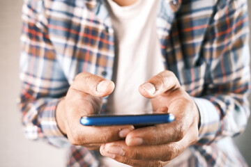 Close up of young man hand using smart phone.