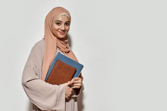 Smiling young arabian woman in hijab with copybook