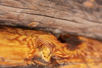 Burnt hewn logs in the wall of the village church. Cracks, knots. Lateral structure of burnt pine log. Selective focus, close-up.