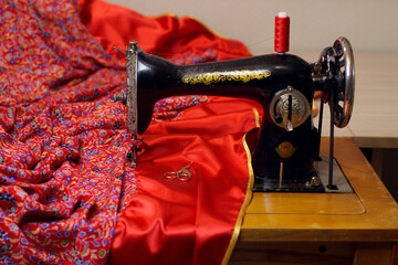A vintage sewing machine and lots of red fabric