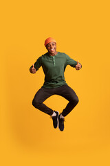 Fototapeta na wymiar Happy Excited Black Guy Jumping And Showing Thumbs Up At Camera