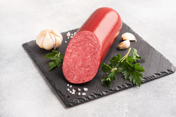A loaf of salami Servelat sausage on a cutting Board with parsley and spices and garlic. top view...