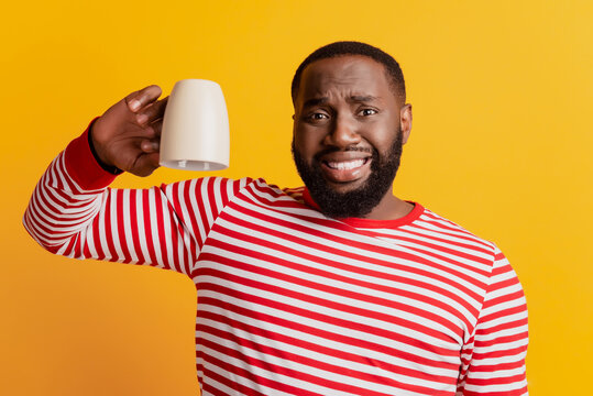 Photo of cheerful grimacing guy hold empty cup on yellow background - Powered by Adobe