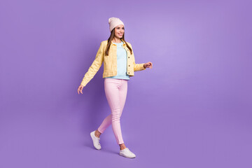 Full length body size photo of charming woman in stylish clothes walking forward smiling isolated on pastel violet color background